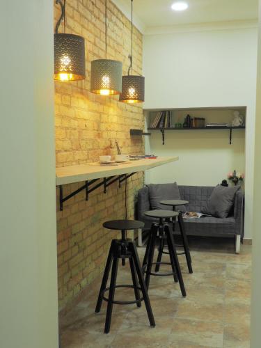 Una barra con tres taburetes y una pared de ladrillos. en Emi apartment, en Vilna