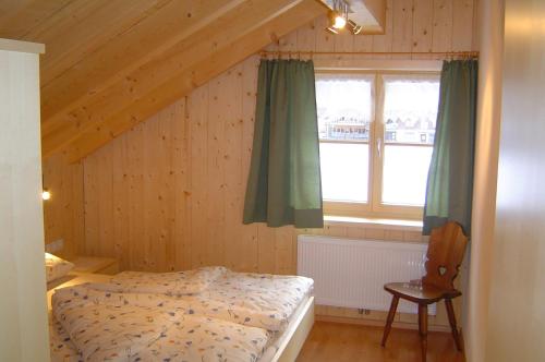 ein Schlafzimmer mit einem Bett, einem Fenster und einem Stuhl in der Unterkunft Ferienbauernhof Beer in Schoppernau