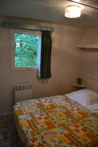 een slaapkamer met een groot bed en een raam bij mobil home du houx in Châtignac
