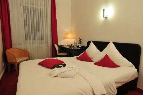 a bed with red pillows and a dog laying on it at Cerano City Hotel Köln am Dom in Cologne