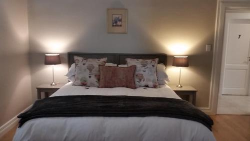a bedroom with a bed with pillows and two lamps at Amberhall Guesthouse in Johannesburg