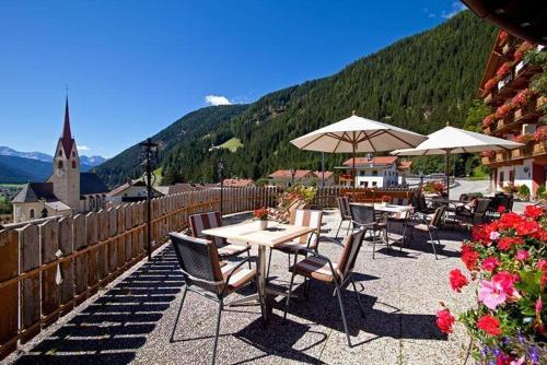 a group of tables and chairs with umbrellas on a patio at Hotel Hofmann in Santa Maddalena in Casies