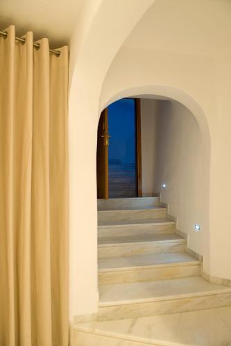 a hallway with stairs and an archway with curtains at Gold Suites - Small Luxury Hotels of the World in Imerovigli