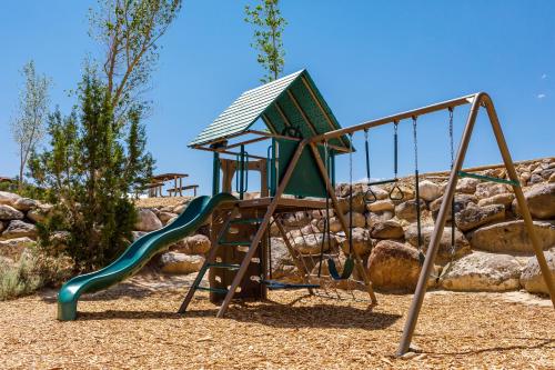 a playground with a slide in front of a rock wall at Escalante Cabins & RV Park in Escalante
