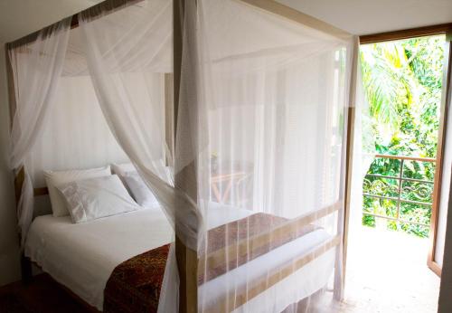 a bedroom with a canopy bed and a window at Estalagem Camburi in Camburi