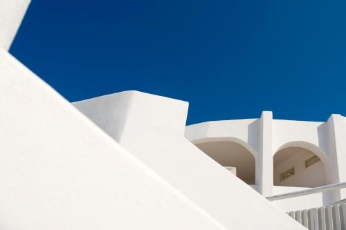 a white building with a blue sky in the background at Gold Suites - Small Luxury Hotels of the World in Imerovigli
