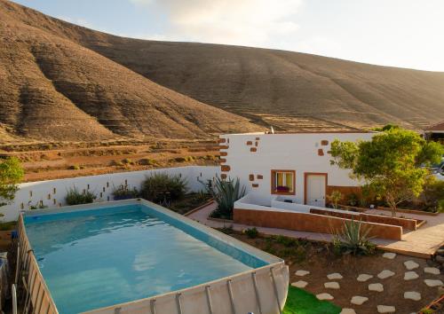 a house with a swimming pool in front of a mountain at Kikiki House in Puerto del Rosario