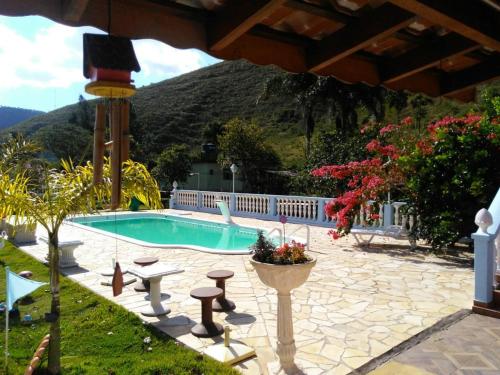 a swimming pool in a yard with a mountain in the background at Pousada 7 Estrelas in Ipiabas