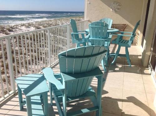 a row of chairs and tables on a balcony with the beach at Sea Oats Condo Unit #202 in Navarre