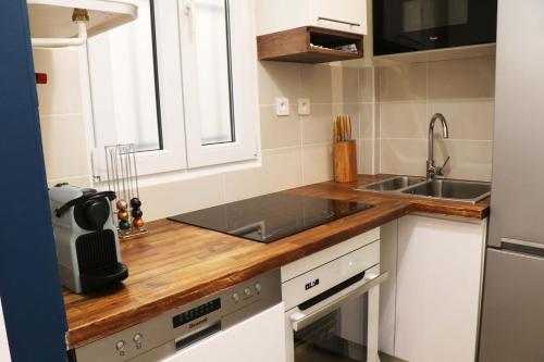 アニエール・シュル・セーヌにあるStayLib - NICE FLAT 2 ROOMSのキッチン(白いキャビネット、木製カウンタートップ付)