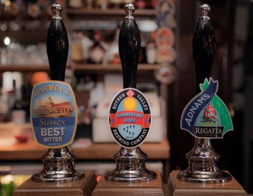 Trois bouteilles de bière assises au-dessus d'un comptoir dans l'établissement The George Inn, à Robertsbridge