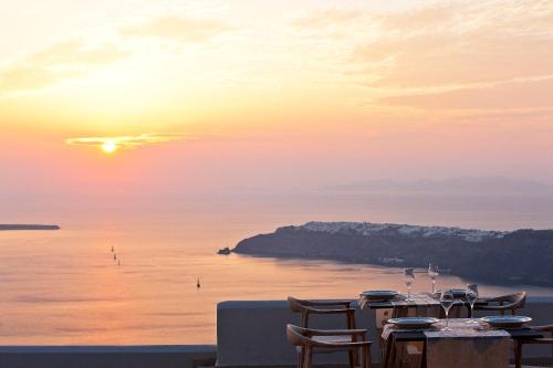 a table with a view of the ocean at sunset at Gold Suites - Small Luxury Hotels of the World in Imerovigli