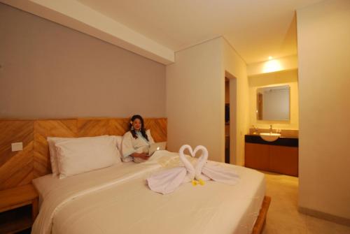 a woman sitting on a bed in a hotel room at DBeds Kuta Beach in Kuta