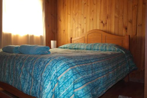 a bedroom with a bed with a blue comforter at Cabañas Los Tamarugos in Pichidangui