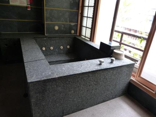 a bathroom with a large granite tub with a window at Full Moon Spa in Wulai