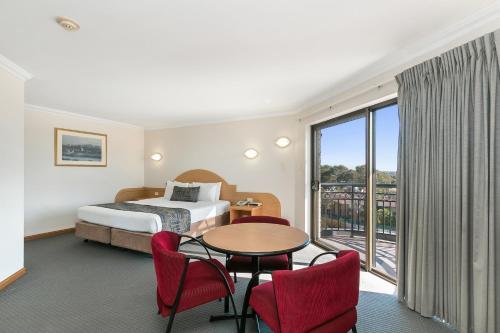 パースにあるGreat Eastern Motor Lodgeのベッド、テーブル、椅子が備わるホテルルームです。