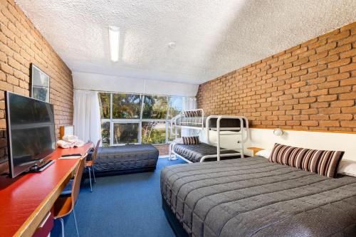 Habitación de hotel con cama y pared de ladrillo en Aquajet Motel, en Coffs Harbour