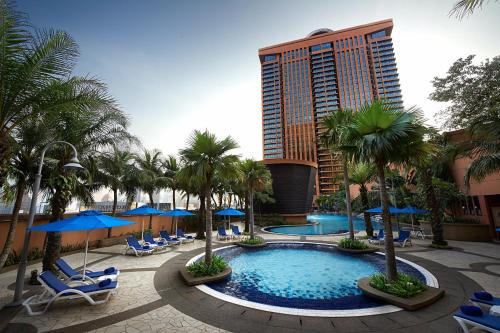 a resort with a pool and palm trees and a tall building at Comfort Service Apartment at Times Square KL in Kuala Lumpur