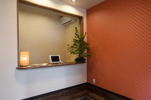 a hallway with a mirror and a laptop on a shelf at Ryokan Ichinao in Tokyo