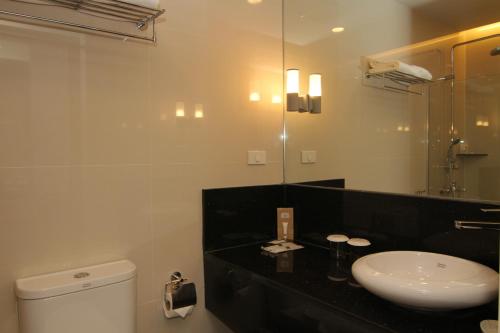 y baño con lavabo, aseo y espejo. en Cebu Hotel Plus en Cebú