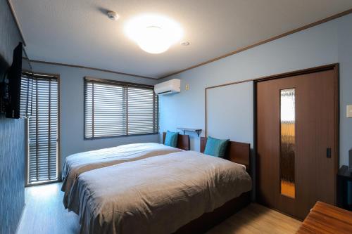 a bedroom with a large bed and two windows at Kulton Moct Kenroku in Kanazawa