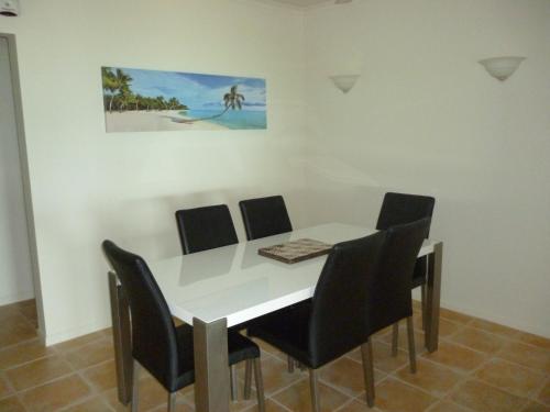 a dining room table with chairs and a painting on the wall at Sea Star Apartments in Airlie Beach