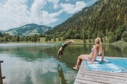 a man and a girl sitting on a dock in the water at Hotel Metzgerwirt in Sankt Veit im Pongau