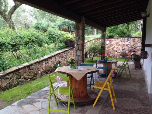 a patio with a table and chairs and a stone wall at Agriturismo Pranu in Sorgono