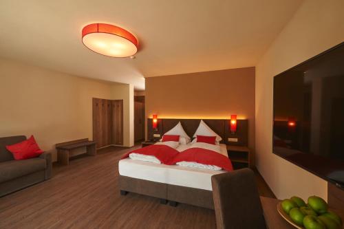 a bedroom with a bed with red pillows and a tv at Hotel Gantkofel in Andrian