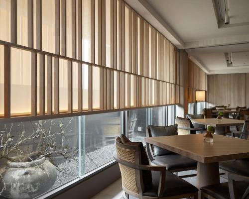a restaurant with tables and chairs and a large window at 礁溪晶泉丰旅 Wellspring by Silks Jiaoxi in Jiaoxi
