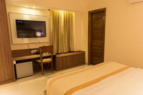 a bedroom with a bed and a desk and a television at Sangai Continental (The Boutique Hotel) in Imphal