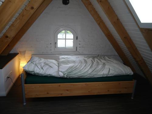 a bed in a attic with a window at Ferienwohnung im Neubauernweg 3 in Hoppegarten