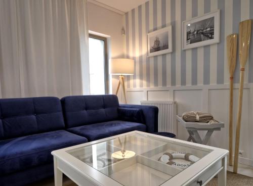 a living room with a blue couch and a table at KOMFORTOWE DOMKI Brzozowa Przystań nad morzem we Władysławowie in Władysławowo