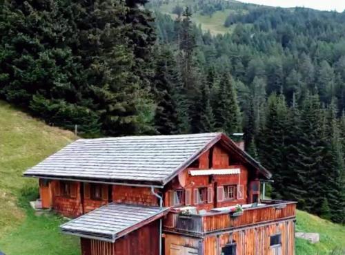 mały drewniany domek na wzgórzu z drzewami w obiekcie Turner-Hütte w mieście Heiligenblut