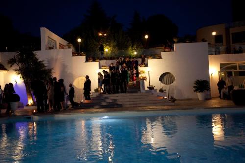 a group of people standing by a pool at night at 501 Hotel in Vibo Valentia