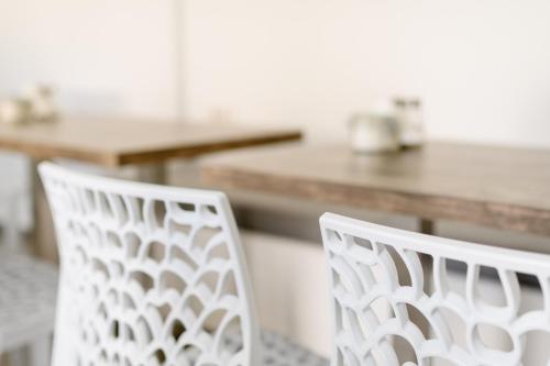 two white chairs sitting in front of a table at Nikolas Hotel in Karterados