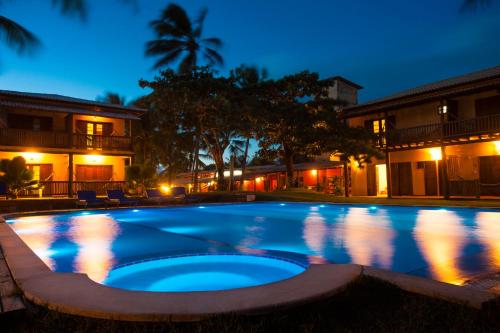 a large swimming pool at night with lights at Pousada Praia das Ondas - Pé na areia in Itacimirim