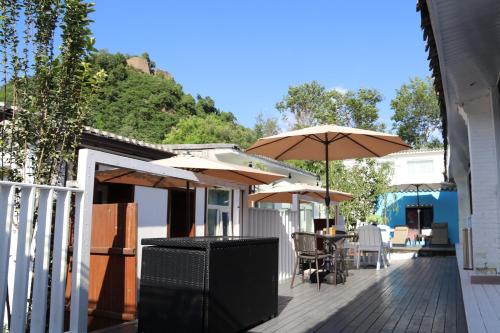 un patio con mesas y sombrillas en una casa en The Great Wall Box House - Beijing, en Miyun