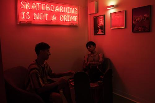 two men sitting in a dark room with a neon sign at Sant Jordi Hostels Sagrada Familia in Barcelona
