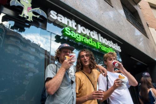 a group of people eating food in front of a store at Sant Jordi Hostels Sagrada Familia in Barcelona