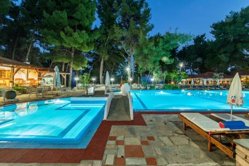 a large swimming pool with a woman standing next to it at Porfi Beach Hotel in Nikiti
