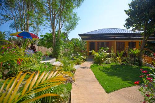 a house with a garden with a pathway and an umbrella at Chekesh Casa in Siquijor