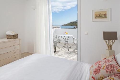 a bedroom with a bed and a balcony with a table at Villa Del Sol Mykonos in Ornos