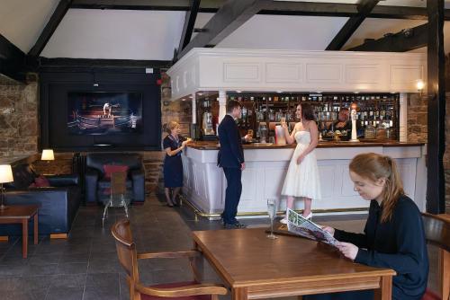 a woman sitting at a table in a bar at Last Drop Village Hotel & Spa in Bolton