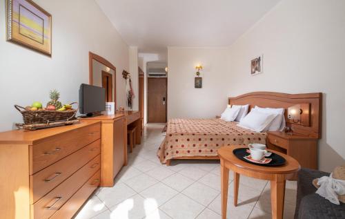 a bedroom with a bed and a table with a tv at Porfi Beach Hotel in Nikiti