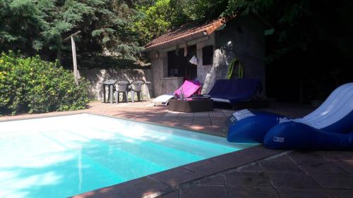 una piscina con 2 sillas azules y una casa en B&B En plein coeur de la forêt en Artiguelouve
