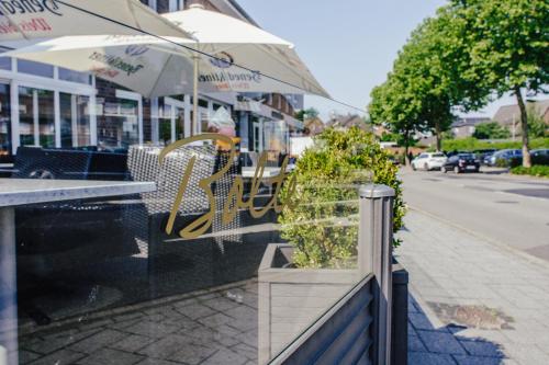 a table and chairs and an umbrella on a street at Hotel Bolte in Salzbergen