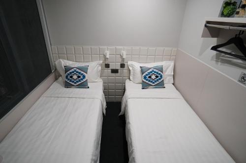 two beds in a small room with white walls at MK STAY - formerly HOTEL MK in Hong Kong