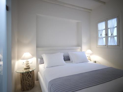 a white bedroom with a white bed and two lamps at Villa Marandi Luxury Suites in Stelida