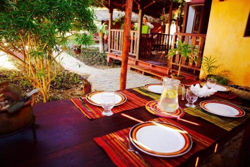a table with plates and glasses on top at Hotel Ambalamanga in Nosy Be